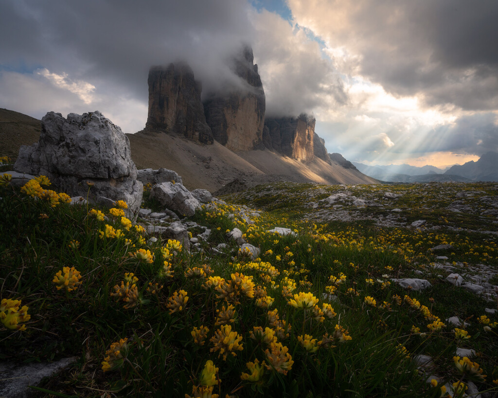 Light rays stream through storm clouds to illuminate Tre Cime in the Italian Dolomites.