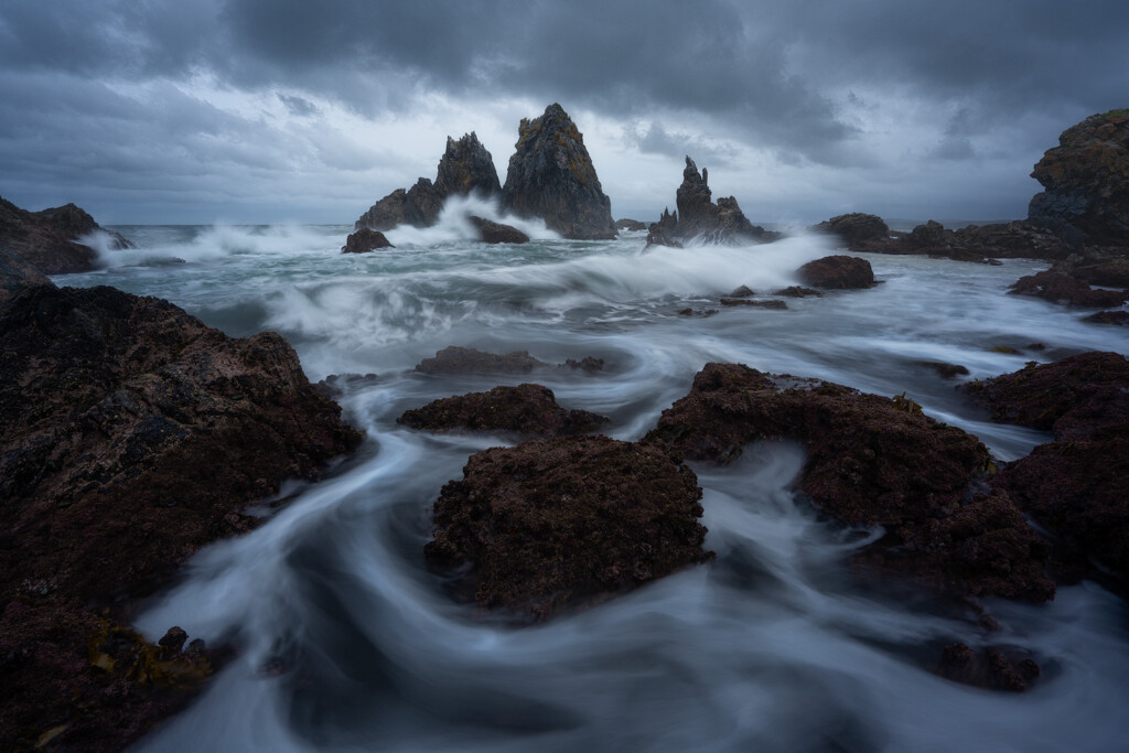 Waves crash against the rugged Camel Rock during a storm.