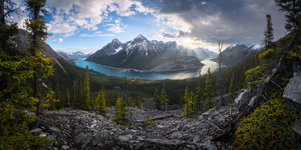 Panorama of a lake wrapping around mountains in the Canadian Rockies at sunset